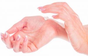 A hand applying cream to another hand